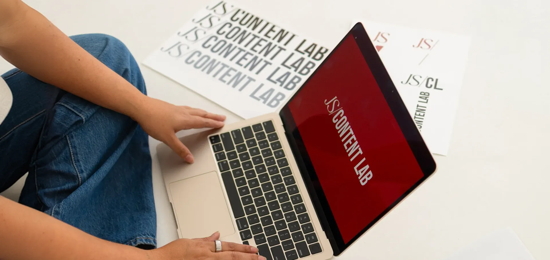 Person working on a laptop next to JS Content Lab print materials